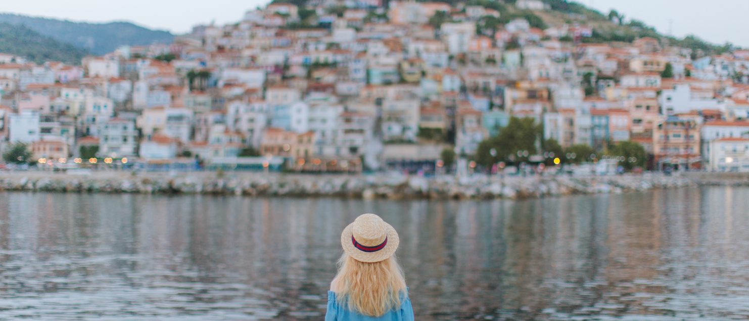 trip planning tips woman sitting next to the sea