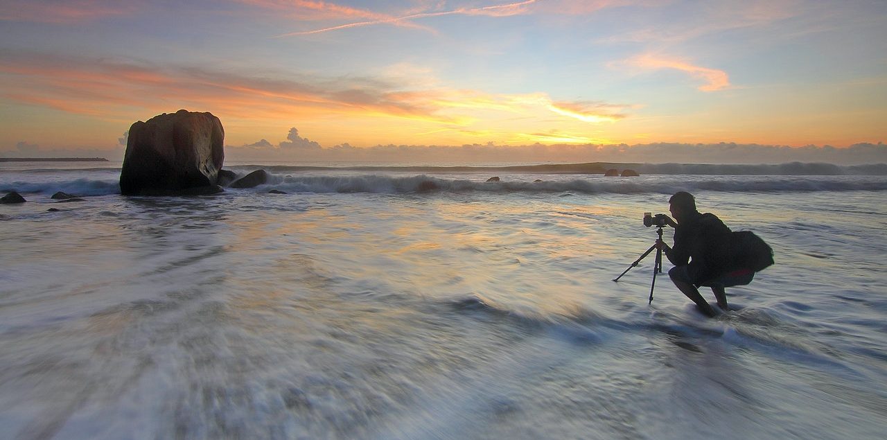 Photographer taking a photo of the sunset on the the water